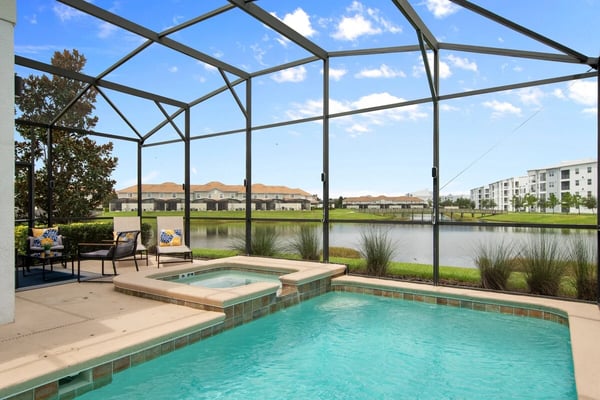 Screened pool and spa overlooking pond and residential community under blue sky
